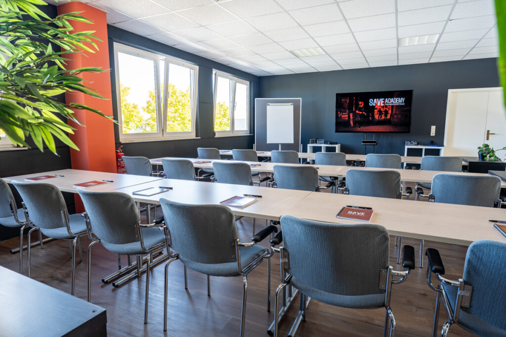 Schulungsraum in der SAVE ACADEMY, Reihenbestuhlung. Im Hintergrund Touch-Display