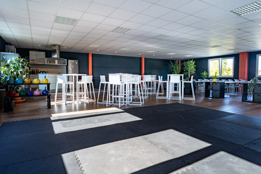 Schulungsraum in der SAVE ACADEMY, Mattenfläche im Vordergrund, dahinter Stehtische und Seminarbestuhlung